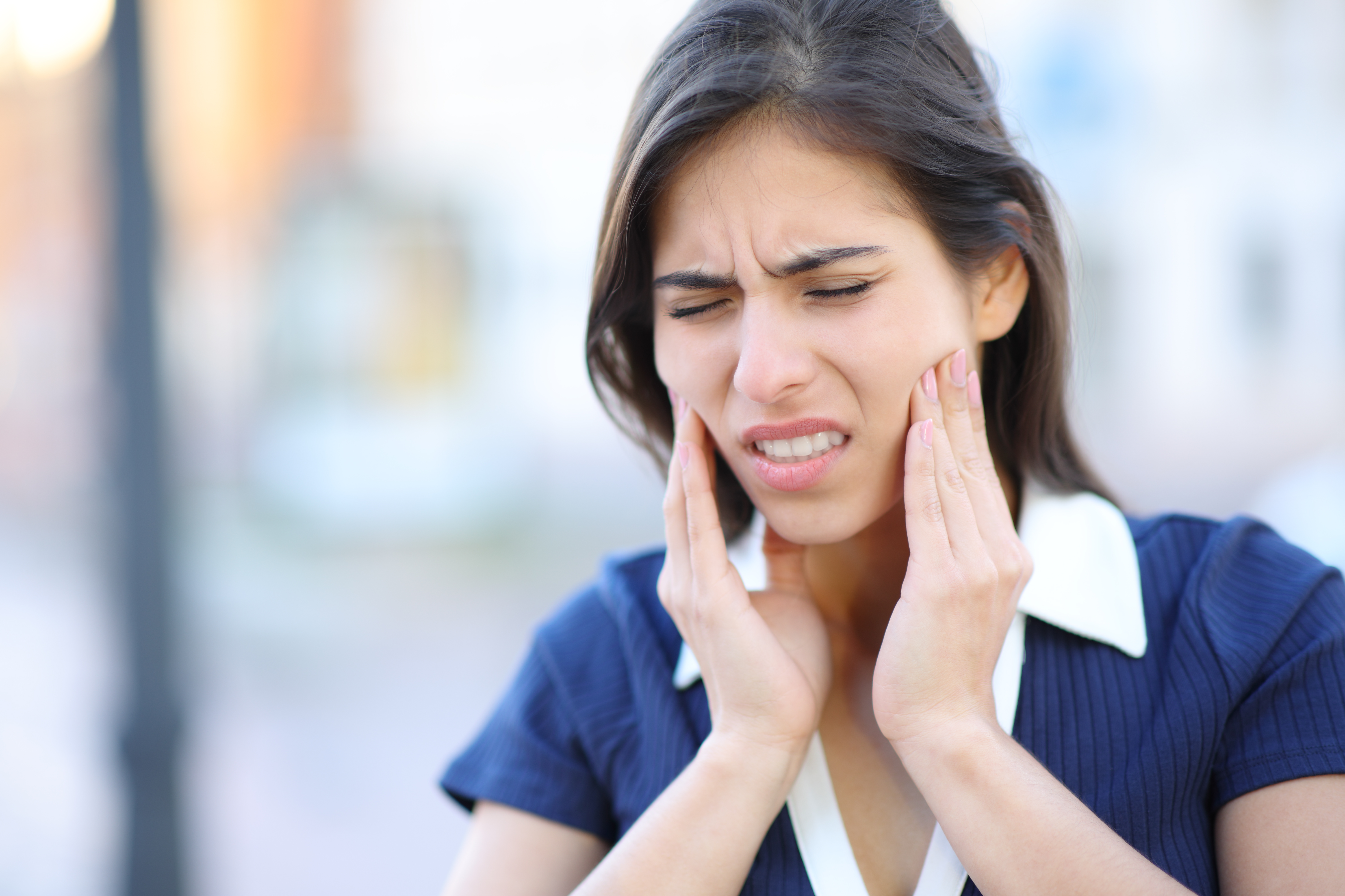 Woman experiencing jaw pain — TMJ symptoms